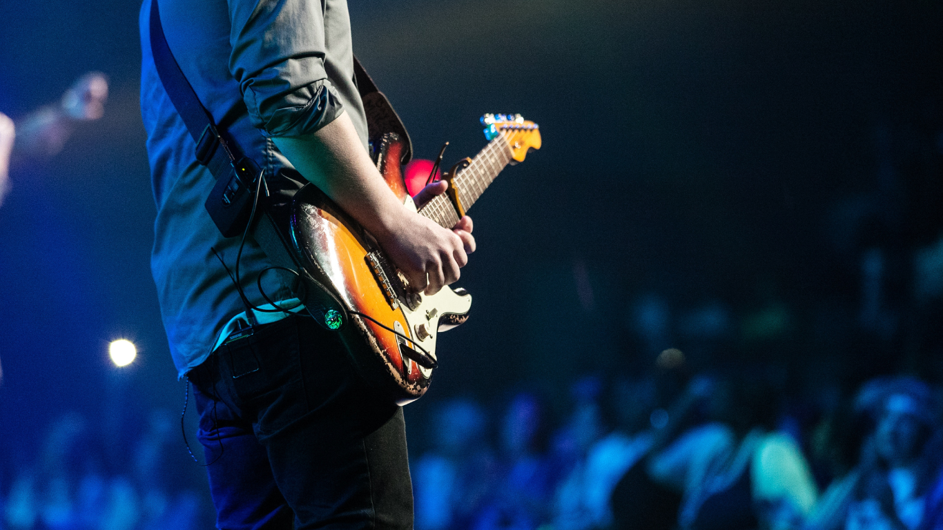 A man is playing an electric guitar on a stage in front of a crowd.