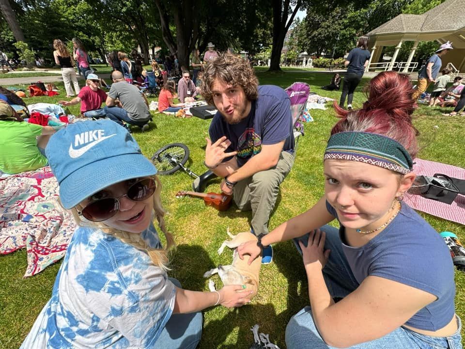 A group of people are sitting on the grass in a park.