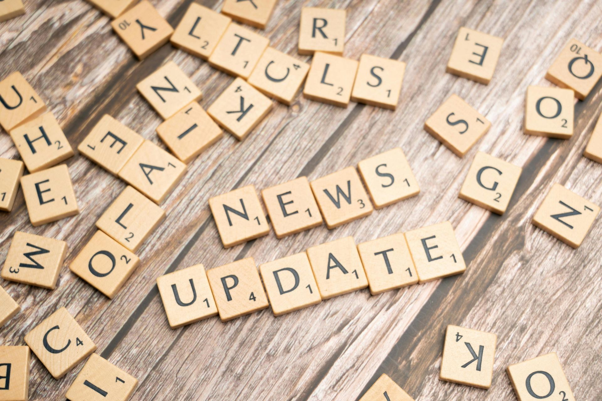 Scrabble tiles spelling ‘NEWS’ and ‘UPDATE,’ surrounded by scattered letters.