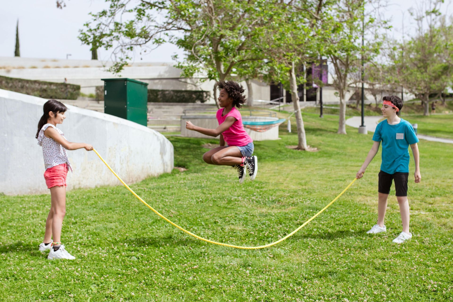 A group of children are jumping a jump rope in a park.