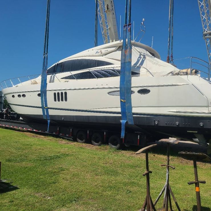 A large white yacht is being lifted by a crane