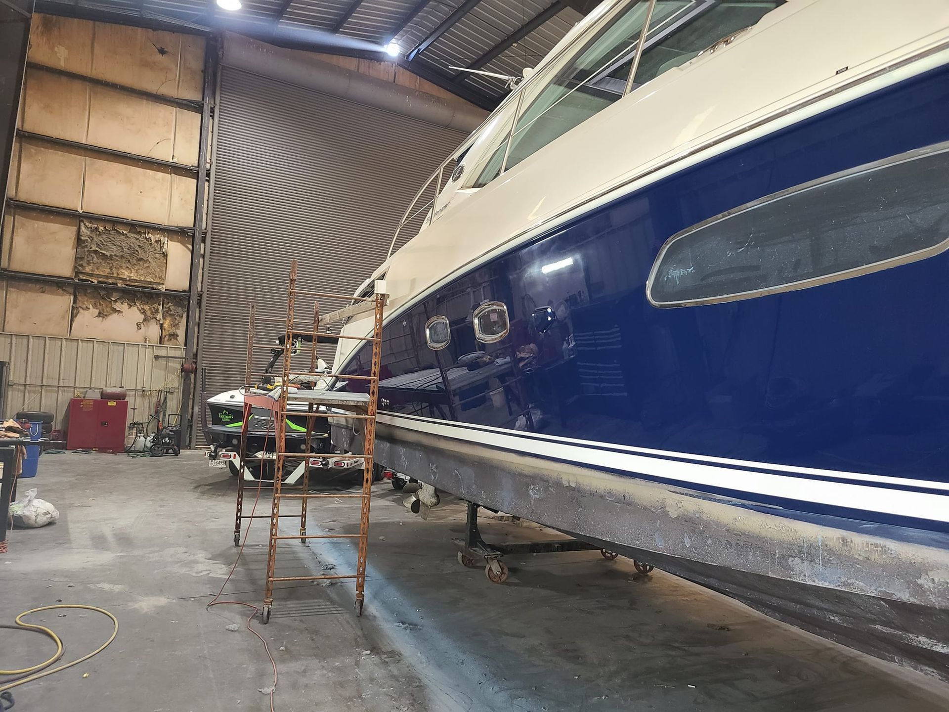 A blue and white boat is sitting in a warehouse.