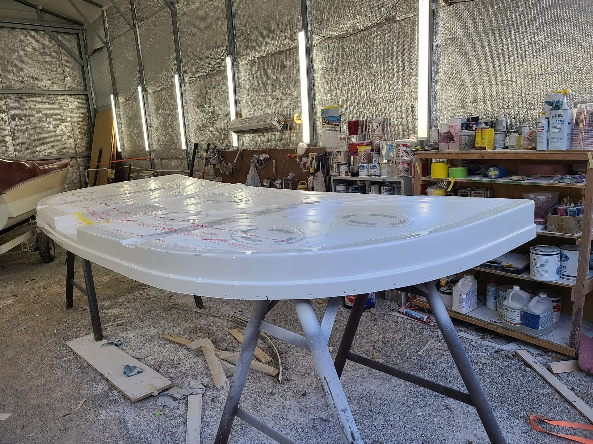 A white table is sitting in a garage next to a boat.