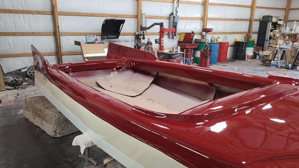 A red and white boat is sitting in a garage.