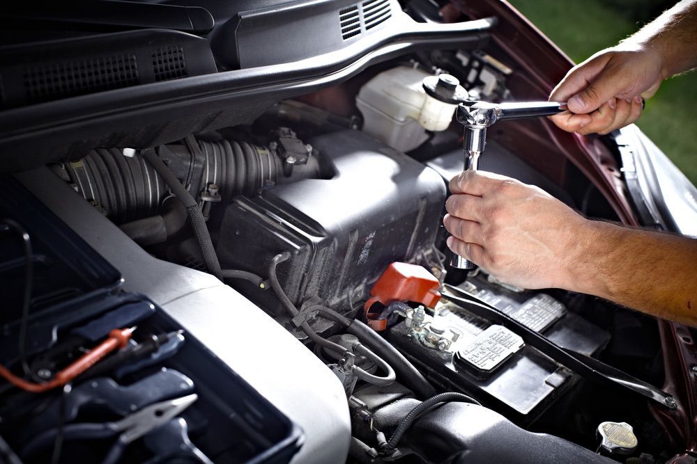 A Man Is Working On The Engine Of A Car With A Wrench — CAL AUTO Mobile Roadworthys in Woodgate, QLD