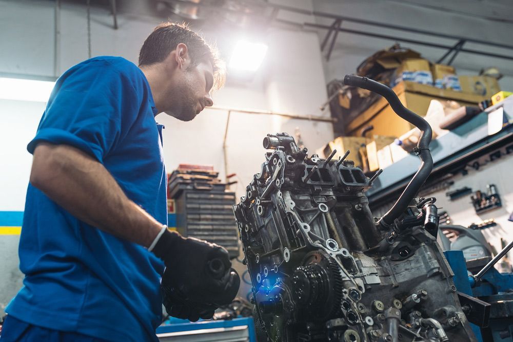 A Man Is Working On A Car Engine In A Garage — CAL AUTO Mobile Roadworthys in Woodgate, QLD