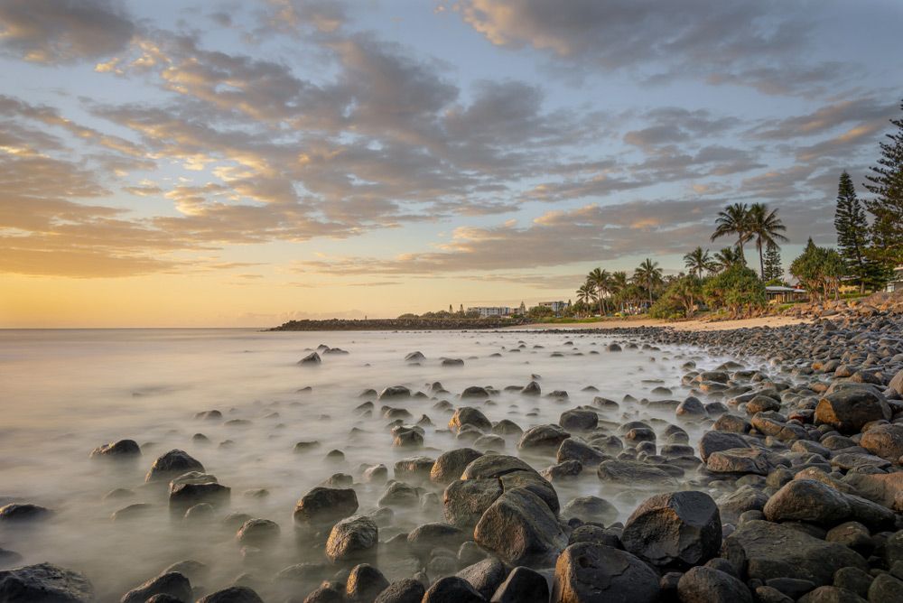 A Long Exposure Photo Of A Rocky Beach At Sunset — CAL AUTO Mobile Roadworthys in Bargara, QLD