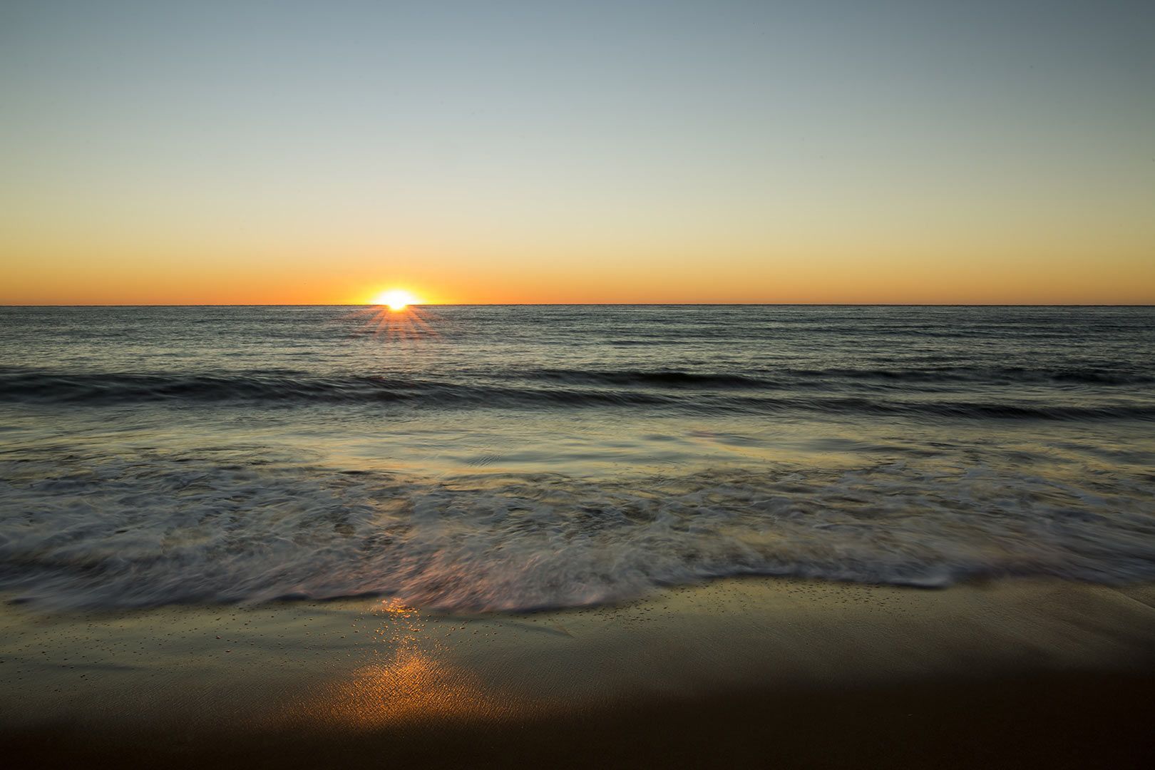 The Sun Is Setting Over The Ocean On A Beach — CAL AUTO Mobile Roadworthys in Bundaberg, QLD