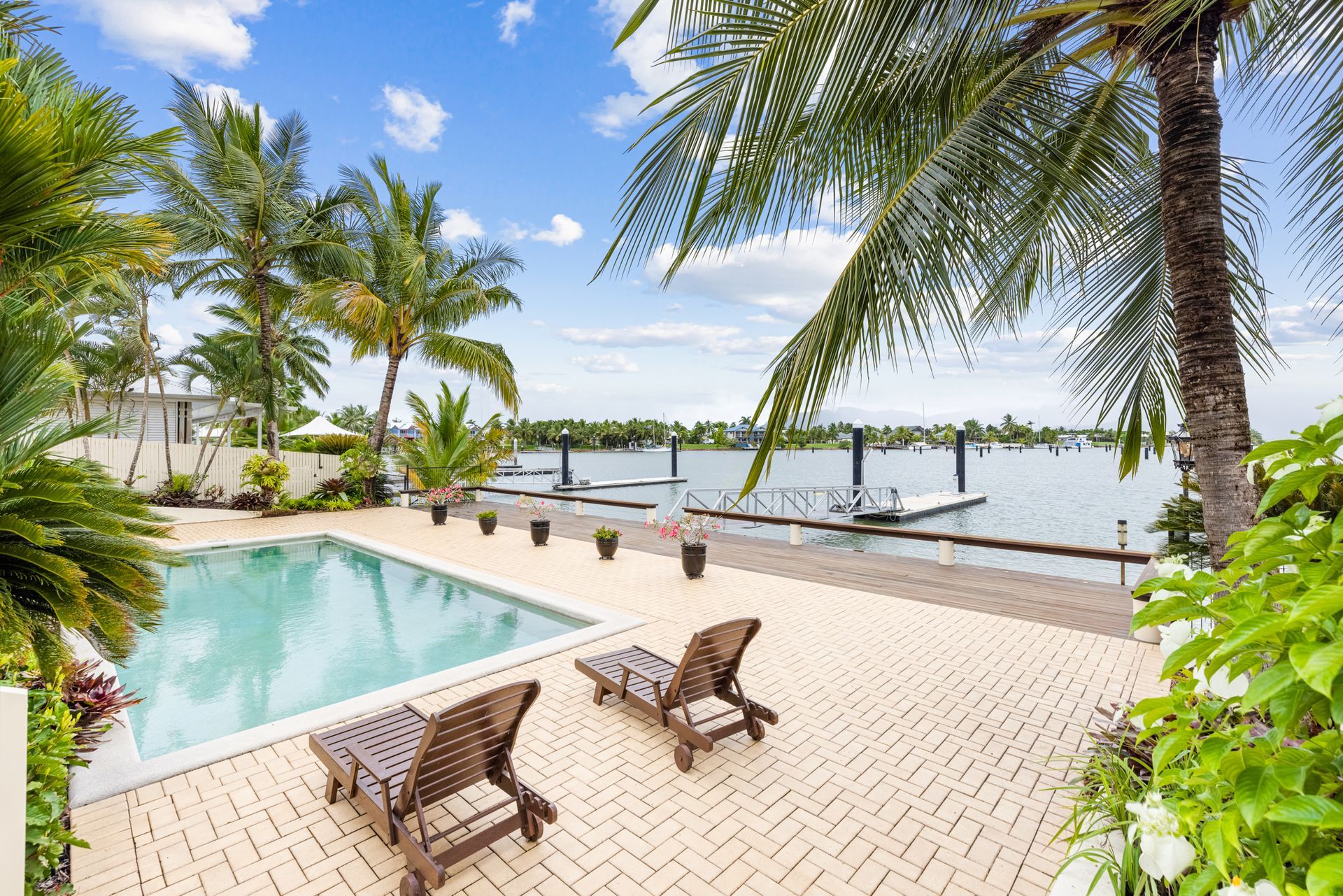 A Swimming Pool Surrounded by Palm Trees and Chairs Next to a Body of Water — MDSR Group in Manunda, QLD