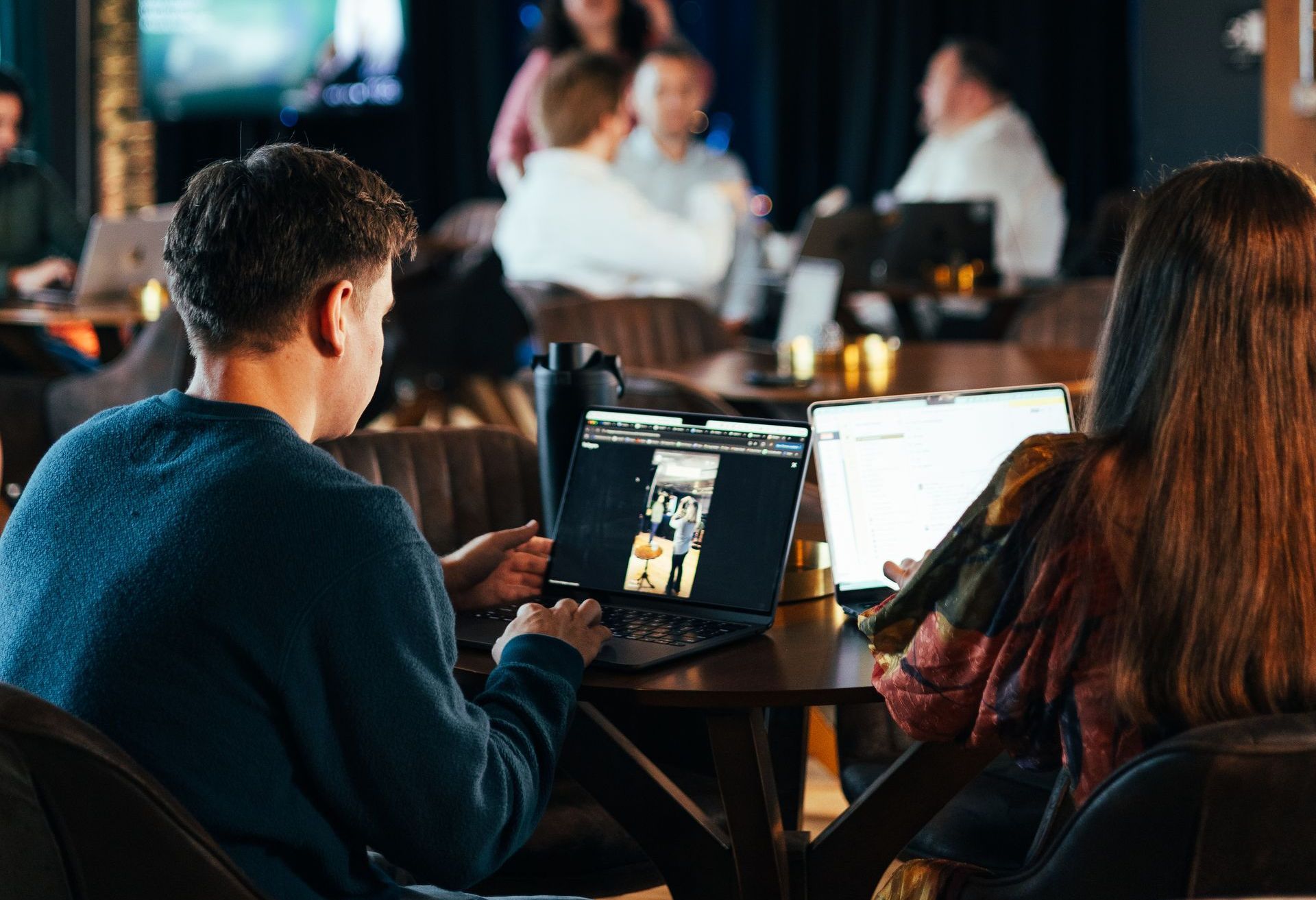 A man and a woman are sitting at a table with a laptop.