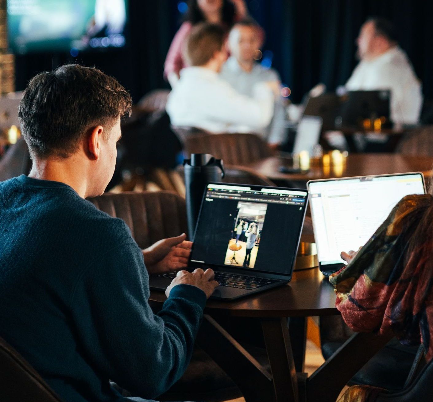 A man is sitting at a table using a laptop computer