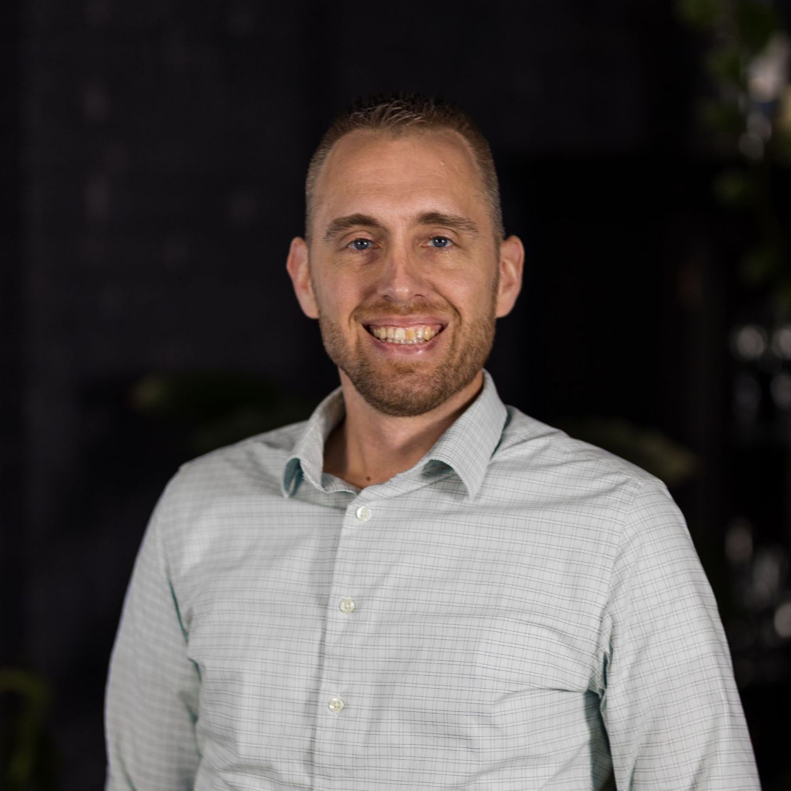 A man in a blue shirt is smiling for the camera
