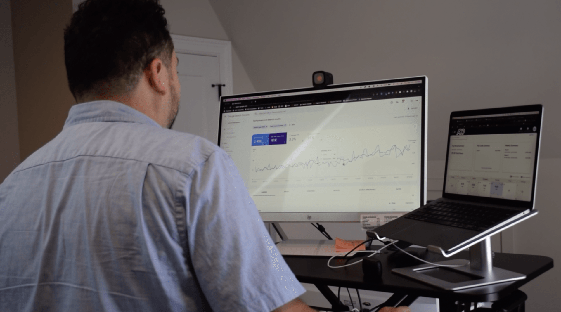 A man is sitting at a desk with a computer and a laptop.