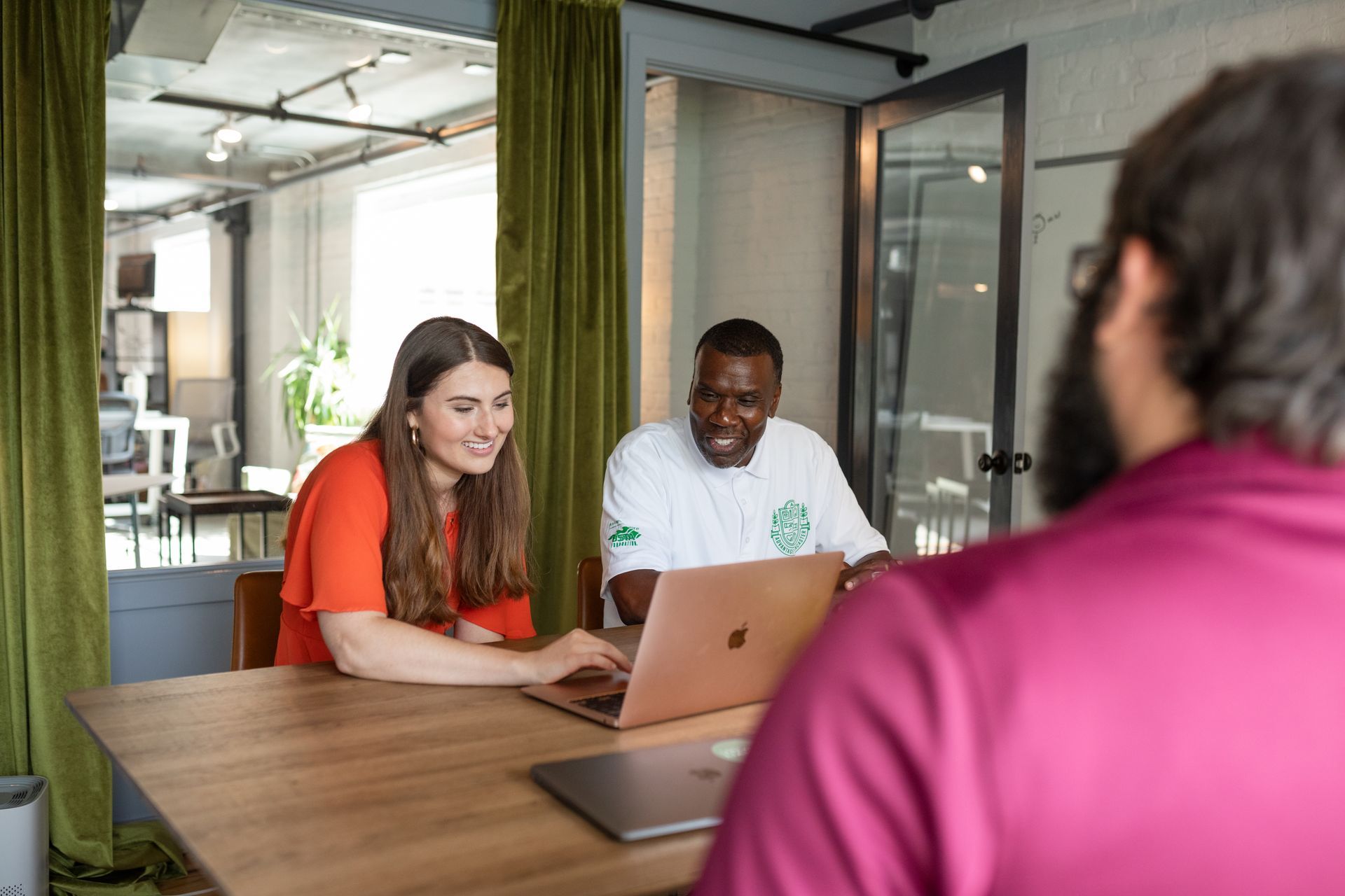 A man and a woman are sitting at a table with a laptop.