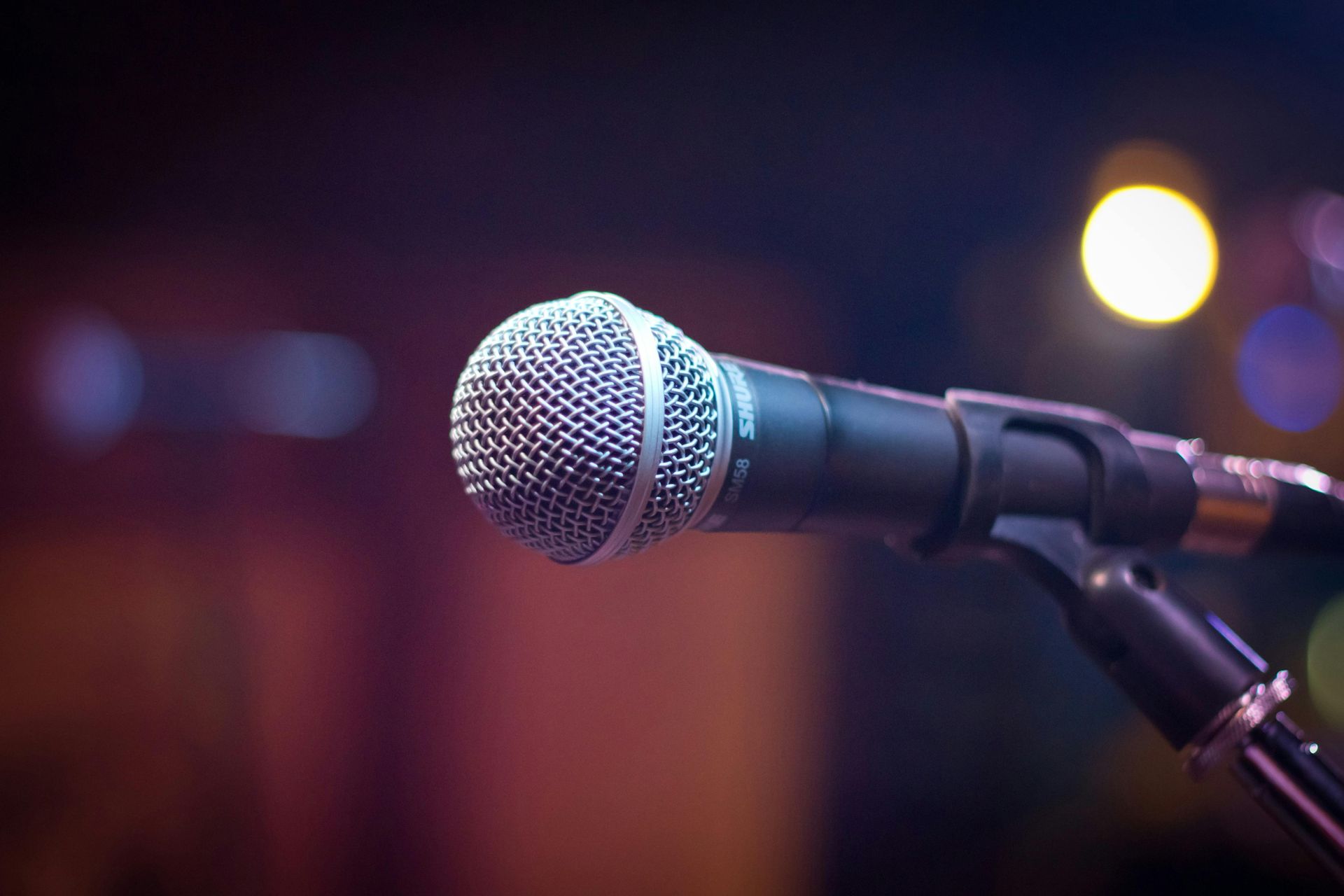 A close up of a microphone on a stand in a dark room.