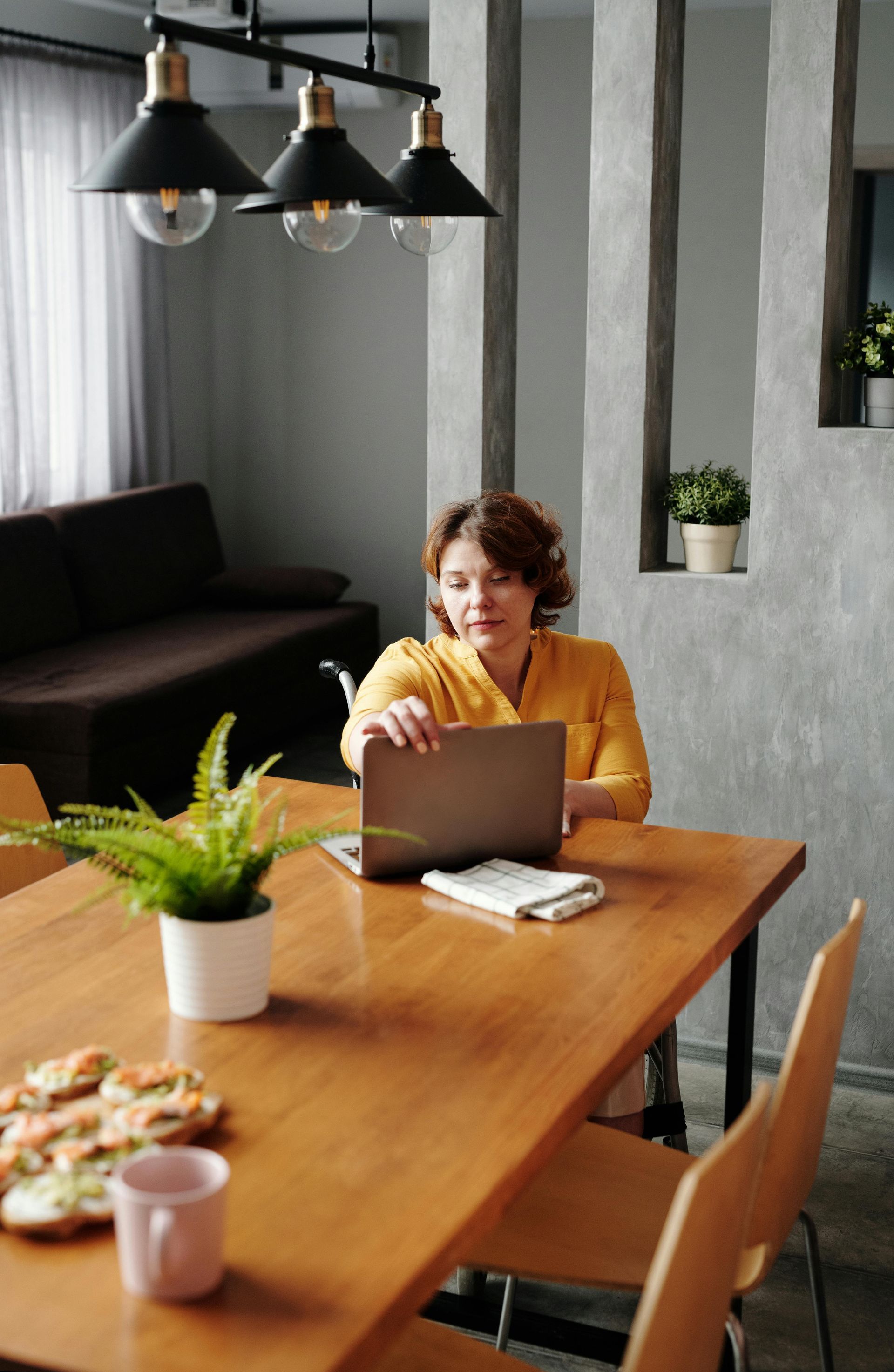 A woman is sitting at a table using a laptop computer.