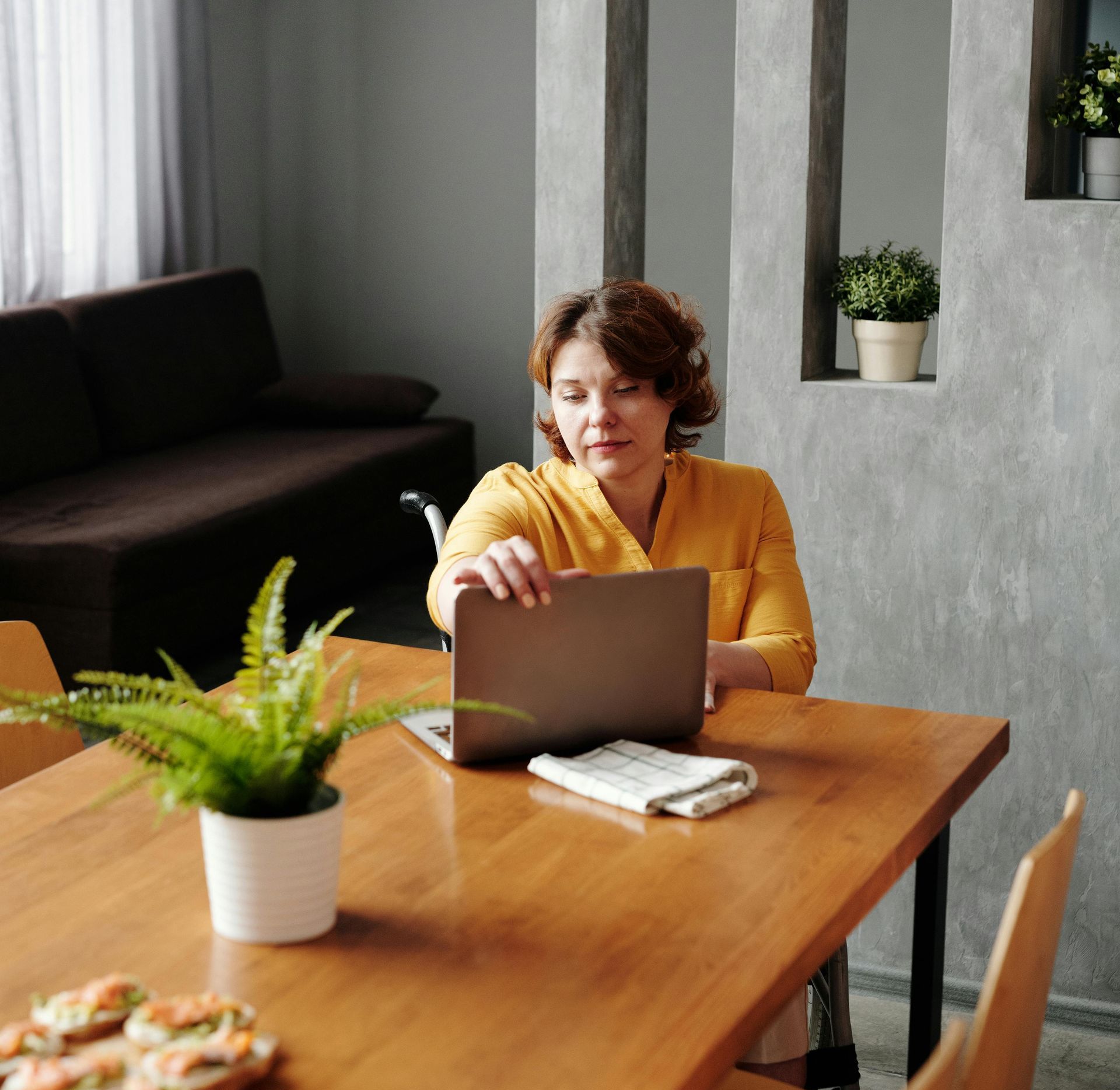 A woman is sitting at a table using a laptop computer.