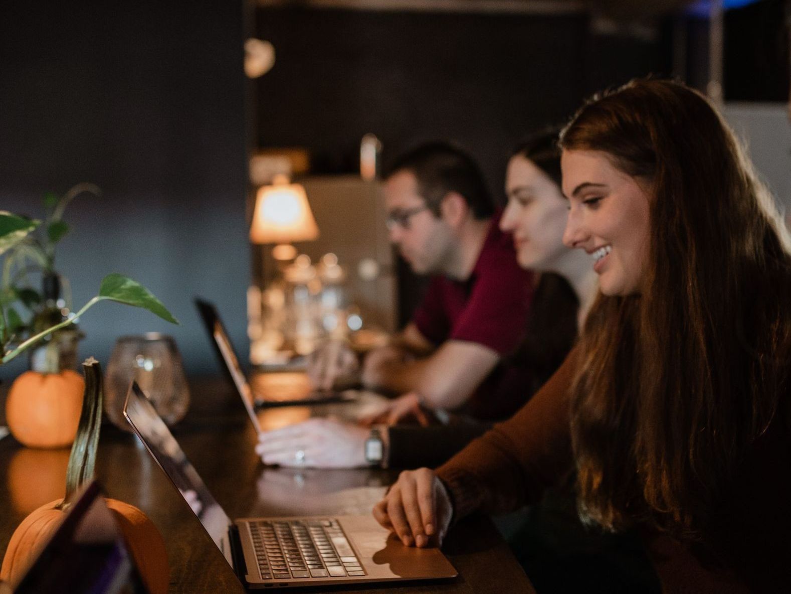 A group of people are sitting at a table using laptops.