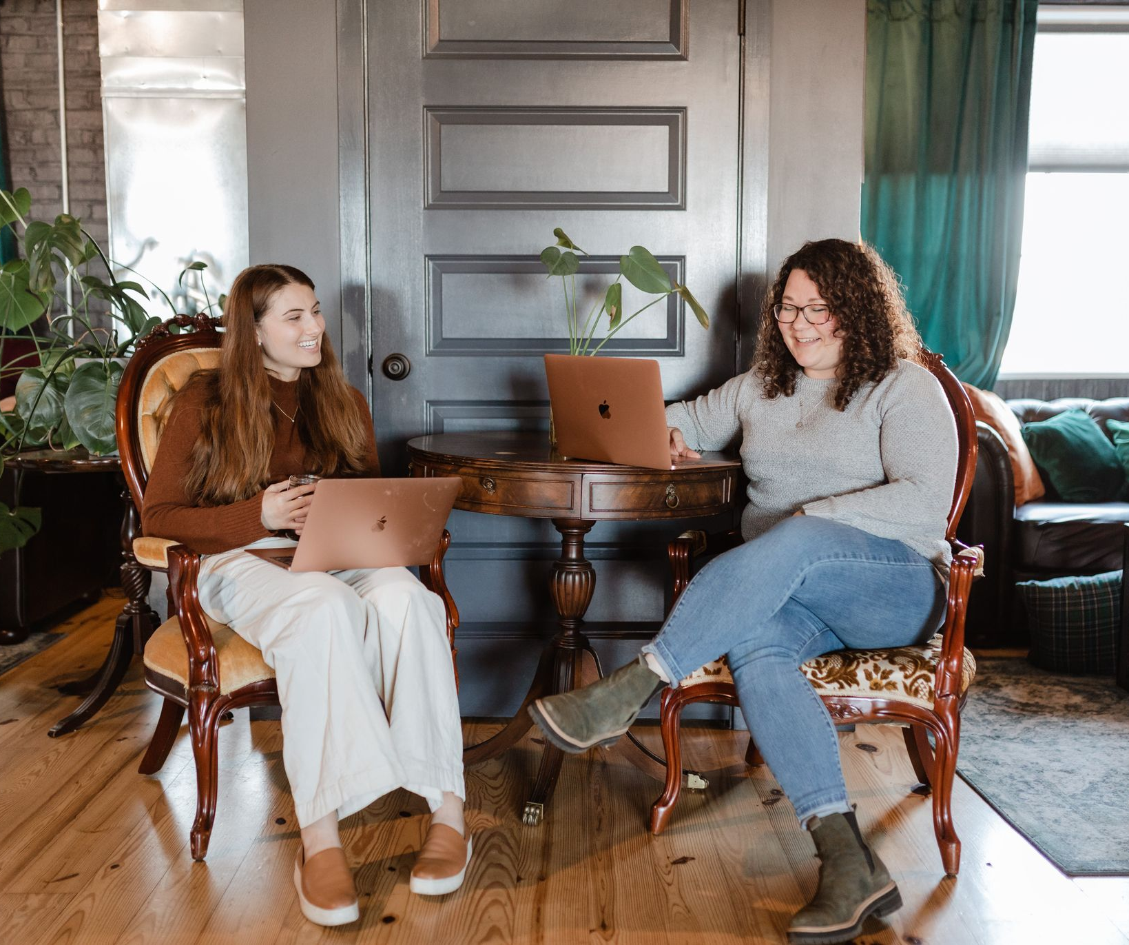 A group of people are sitting around a table with laptops.