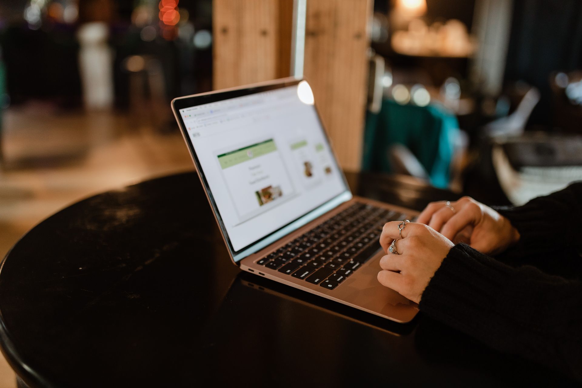 A person is typing on a laptop computer while sitting at a table.