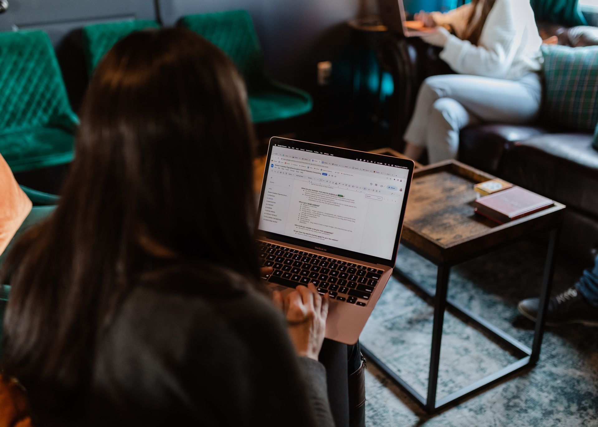 A woman is sitting at a table using a laptop computer.