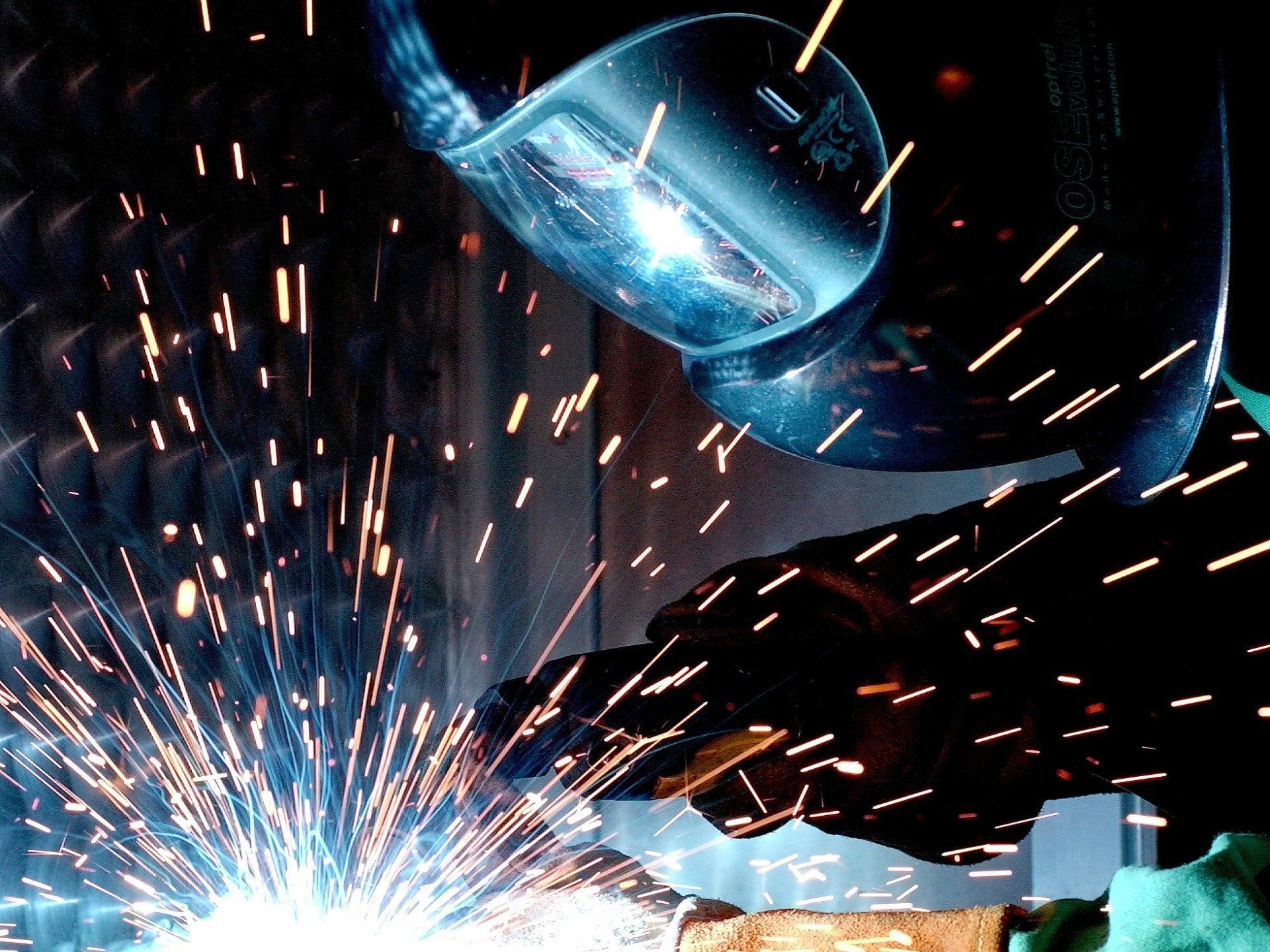 A man is using a grinder to cut a piece of metal on the floor.