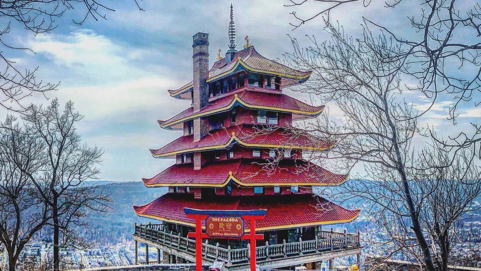 A painting of a pagoda surrounded by trees and a body of water.
