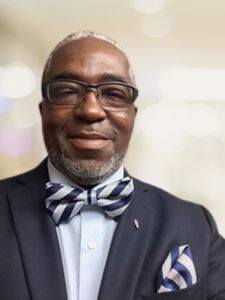 A man in a suit and bow tie is smiling for the camera.