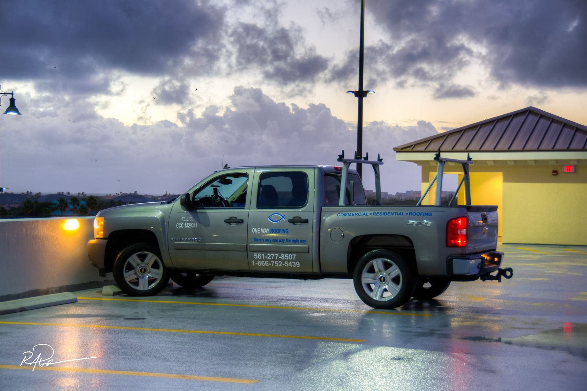 A light brown pickup truck parked on an outdoor parking deck during a cloudy sunset.
