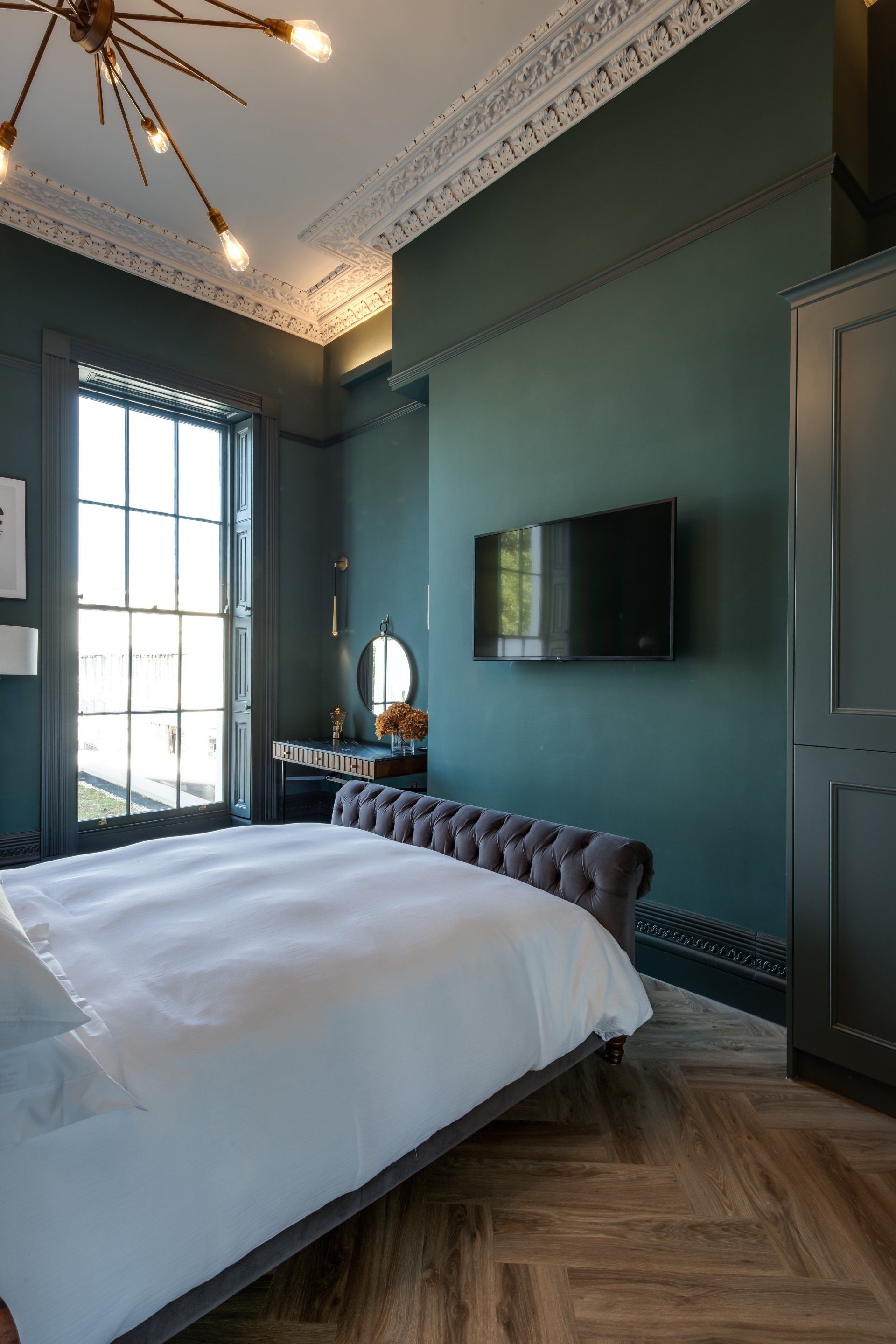 A bedroom with a large bed and a flat screen tv on the wall.