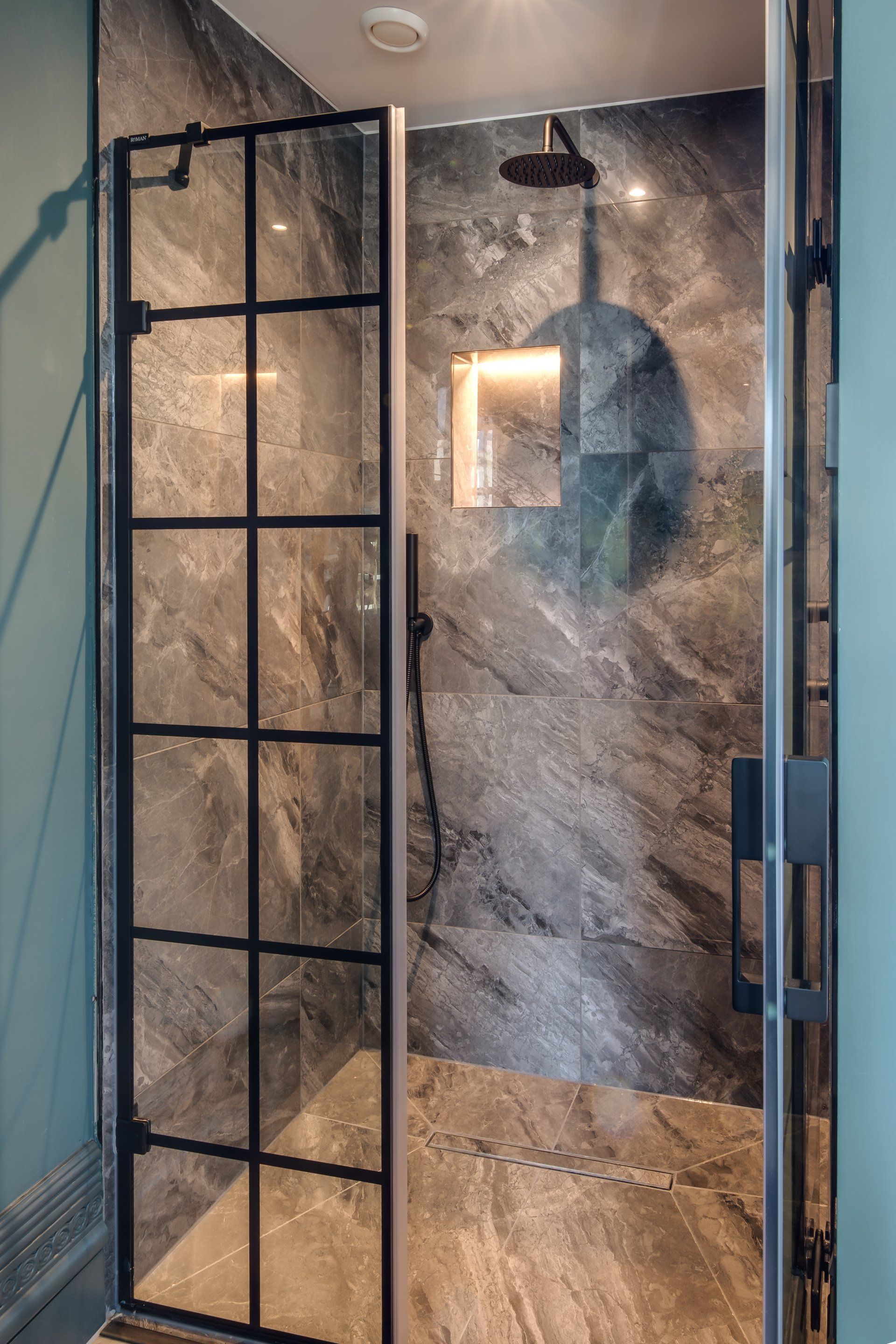 A bathroom with a walk in shower with a black shower door.