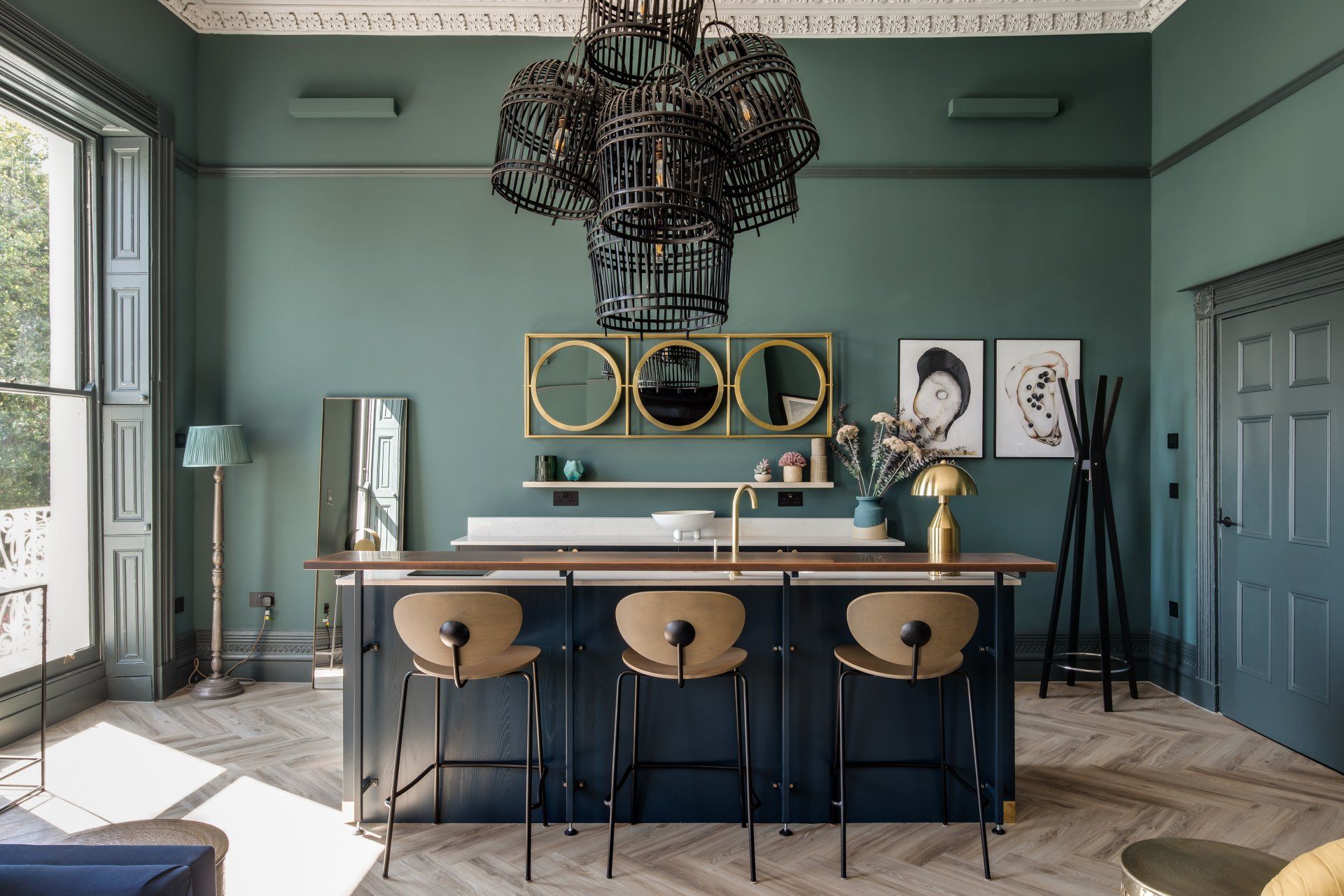 A kitchen with a large island and stools and a chandelier hanging from the ceiling.