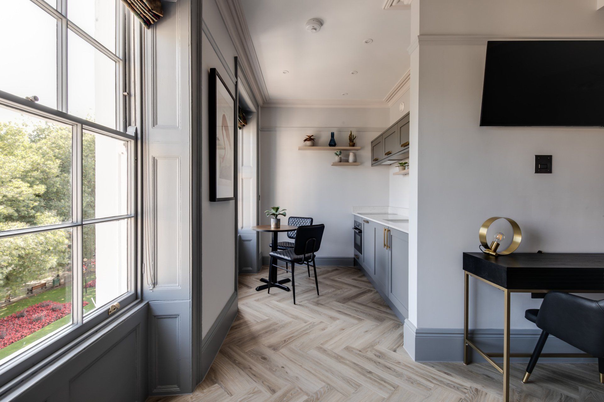 A living room with a desk , chairs , a table and a television.