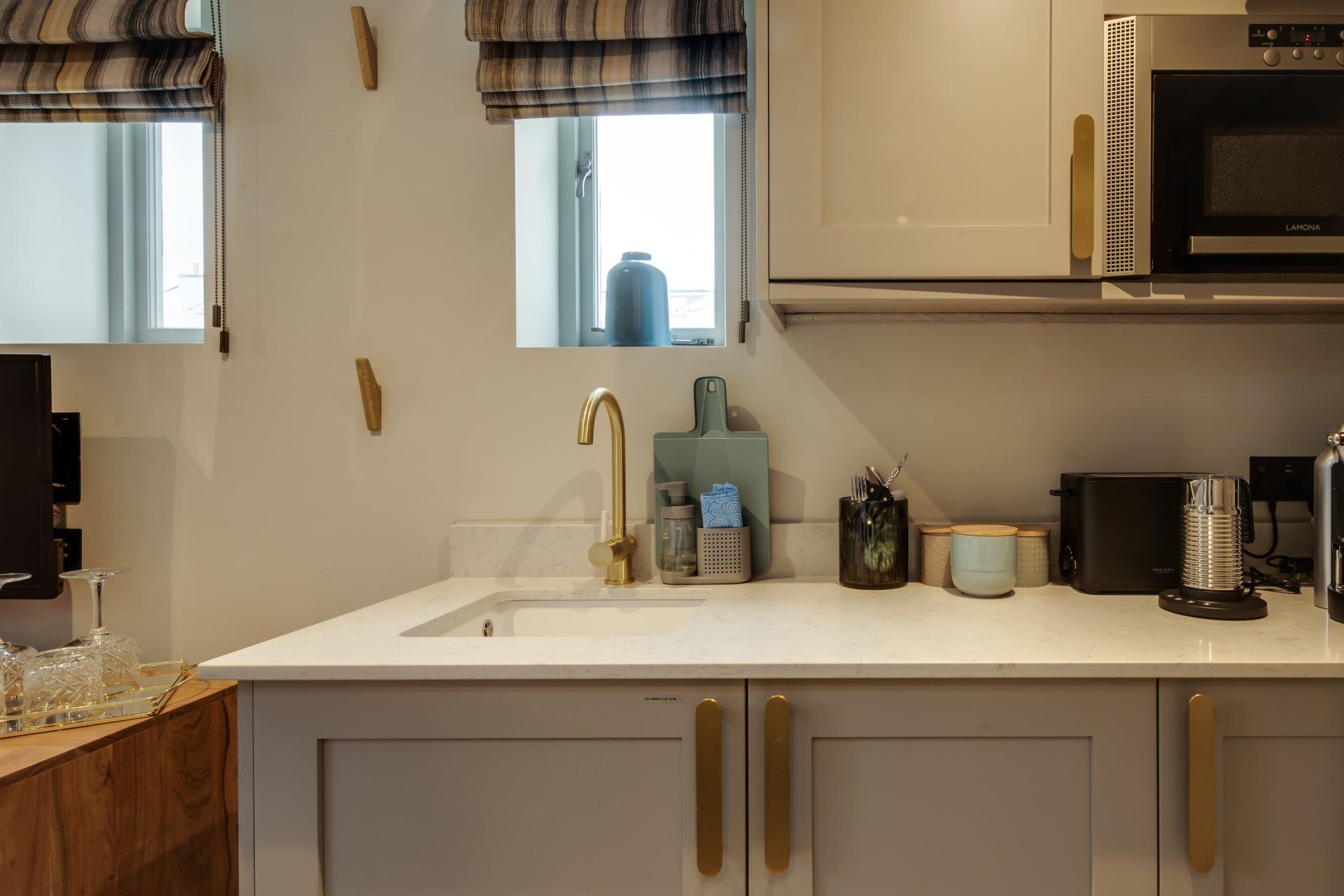 A kitchen with white cabinets , a sink , a microwave , and a window.