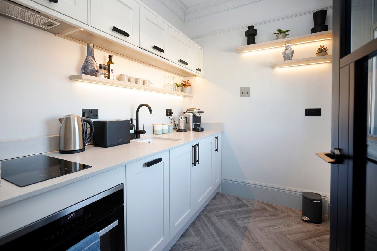 A kitchen with white cabinets , stainless steel appliances , and a stove top oven.