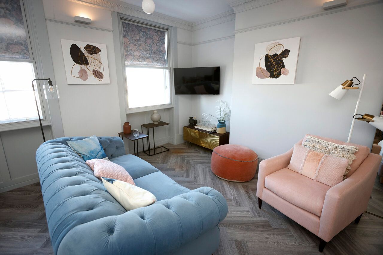 A living room with a blue couch and a pink chair.