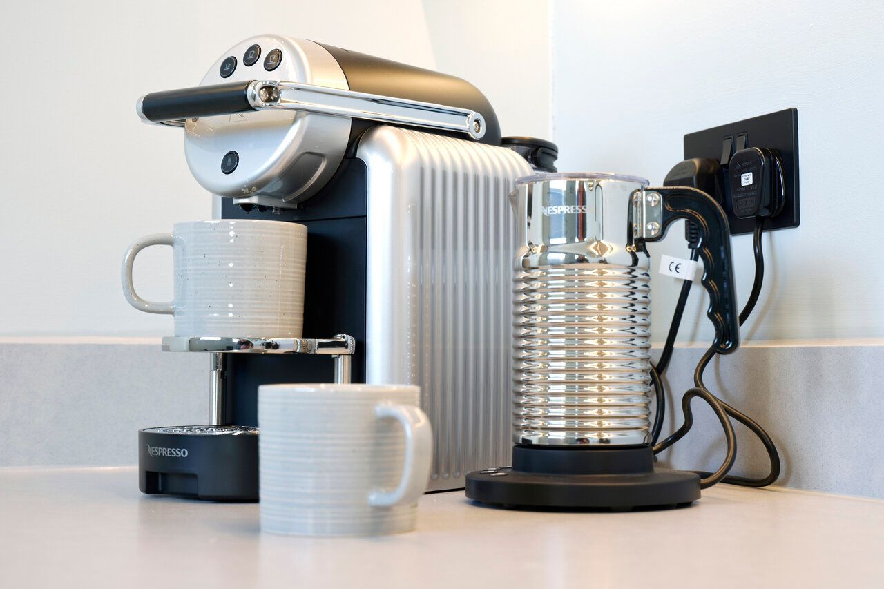 A coffee maker with two cups next to it