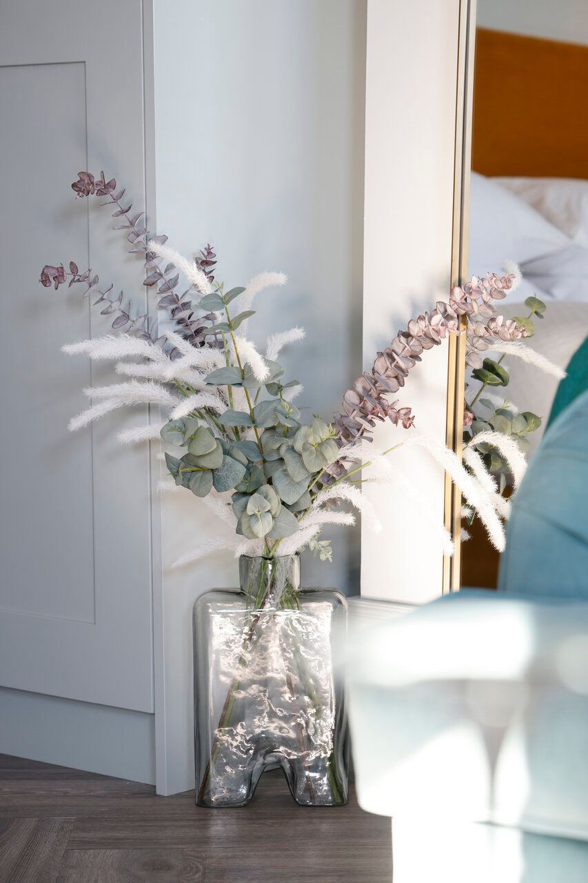 A vase filled with flowers is sitting next to a mirror in a living room.