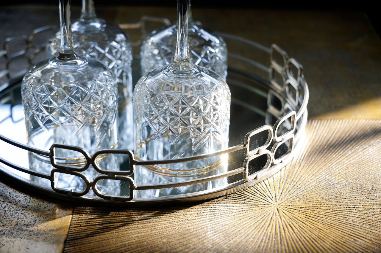 Three wine glasses are sitting on a mirrored tray.