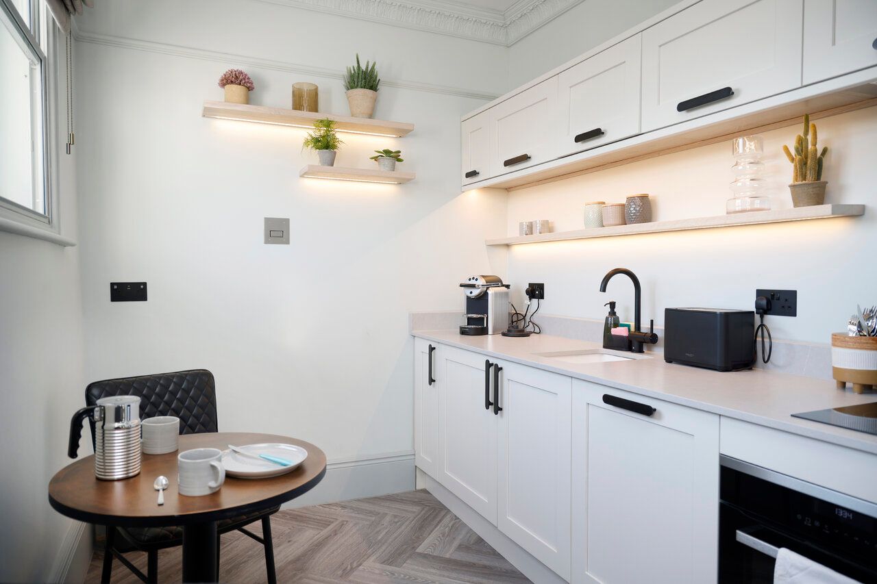A kitchen with white cabinets , a table and chairs.