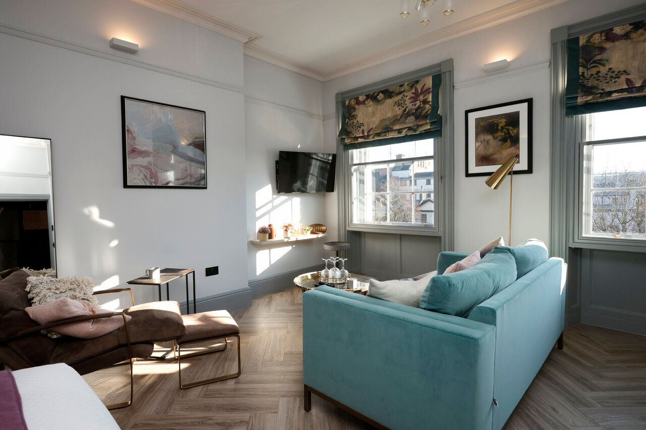 A living room with a blue couch and a brown chair