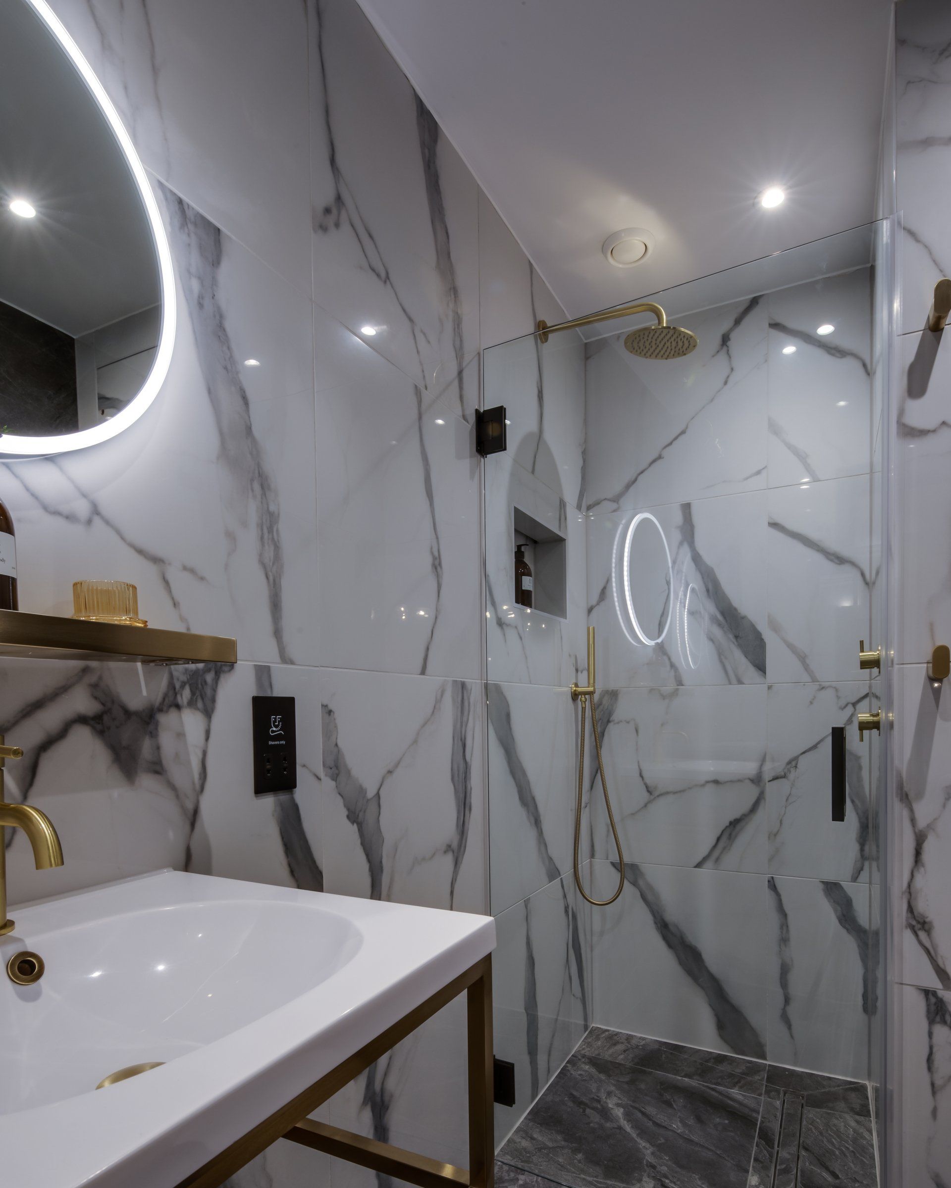 A bathroom with marble walls and a sink and shower