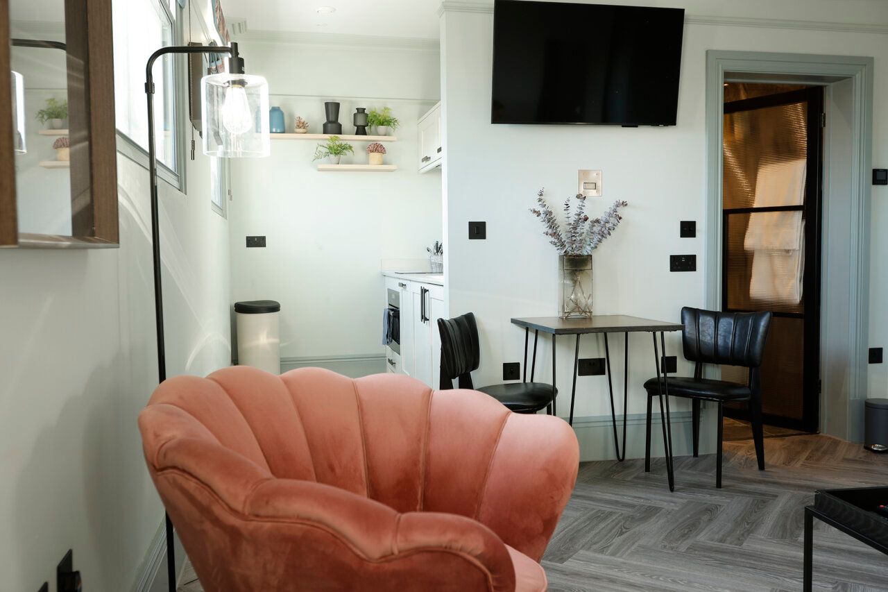 A living room with a pink chair and a flat screen tv