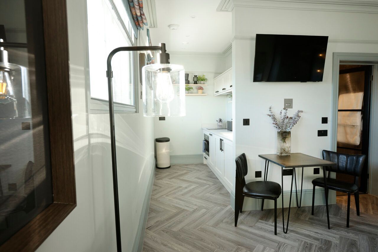 A living room with a table and chairs and a flat screen tv.