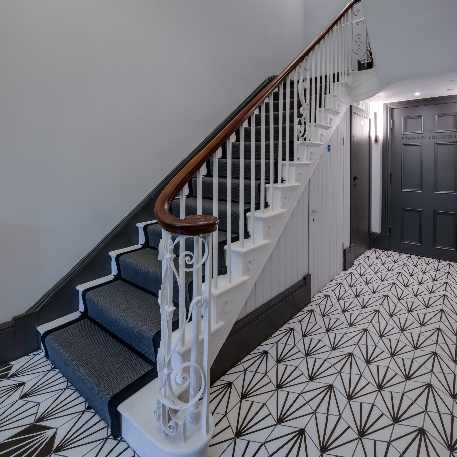 A staircase with a wooden railing and a patterned floor