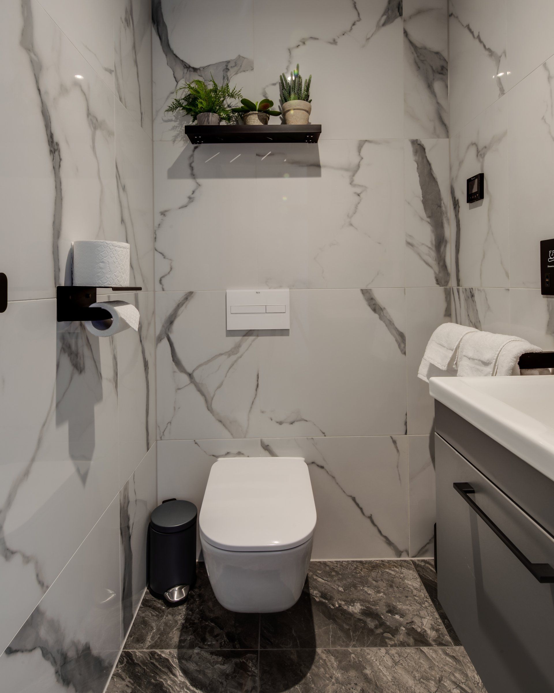 A bathroom with marble walls and a toilet and sink