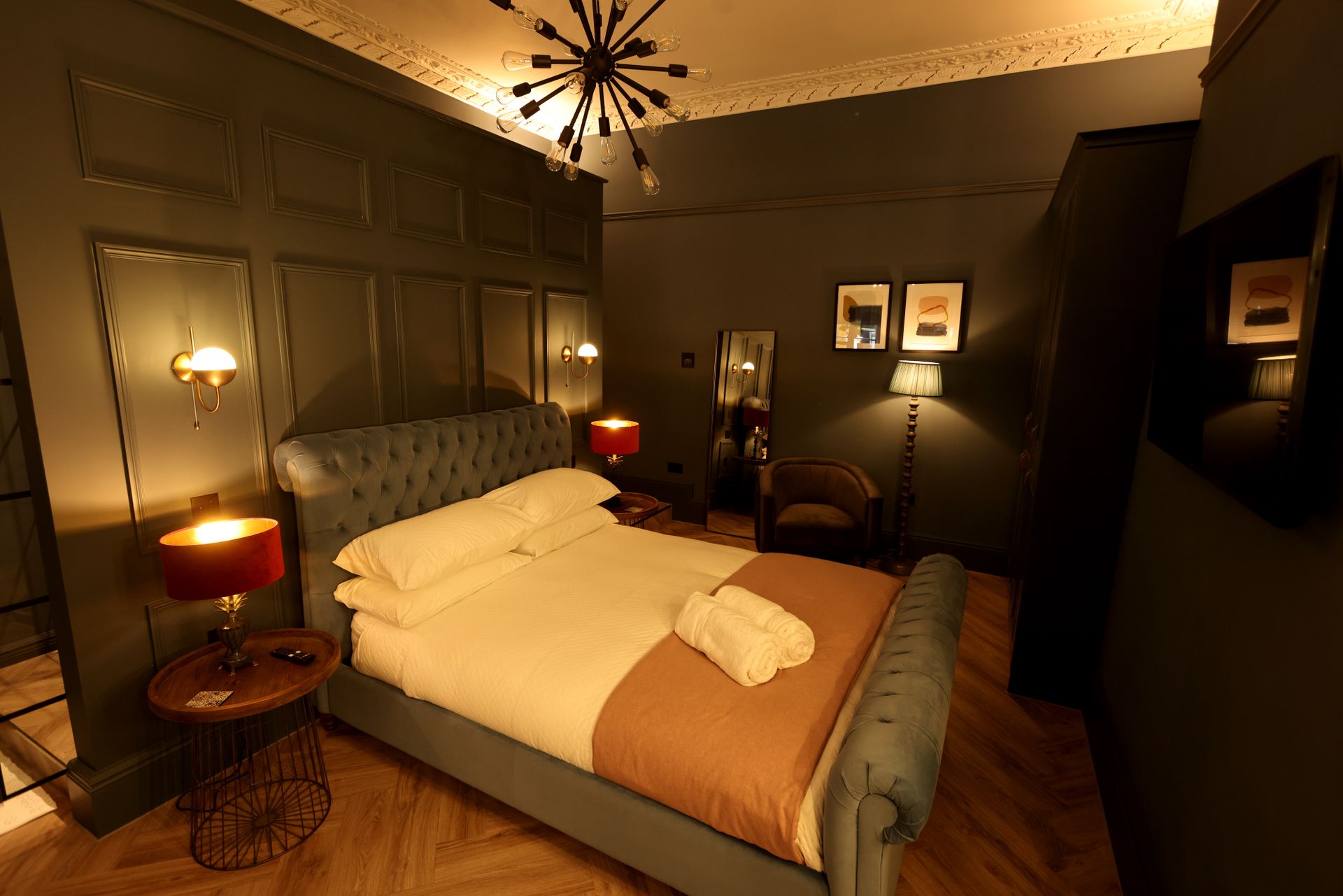 A bedroom with a bed , lamps , a chair and a television.