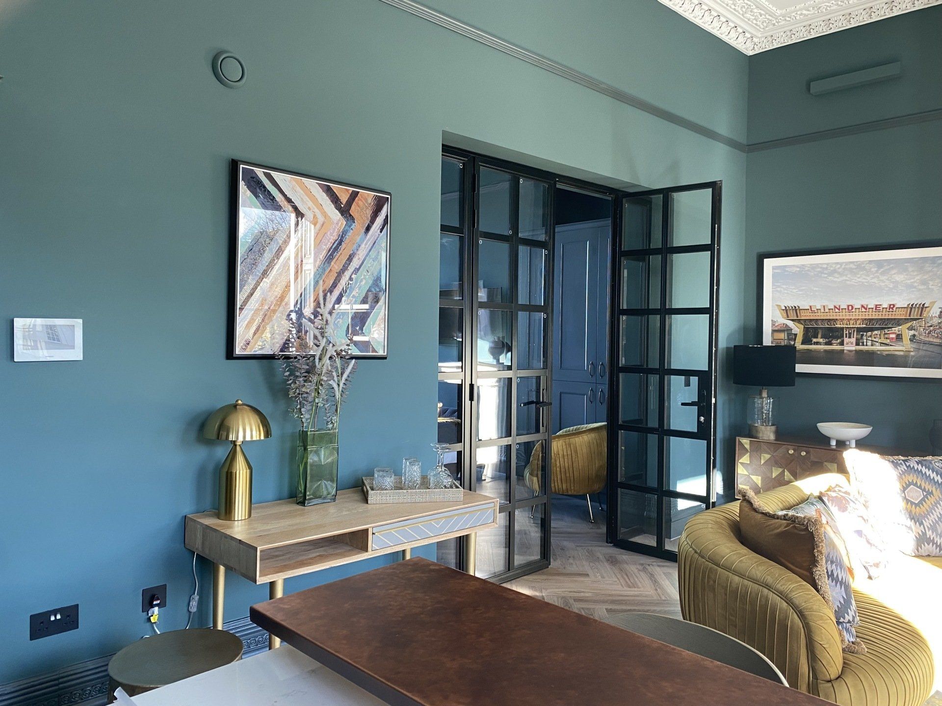 A living room with blue walls , a table , a couch and a picture on the wall.