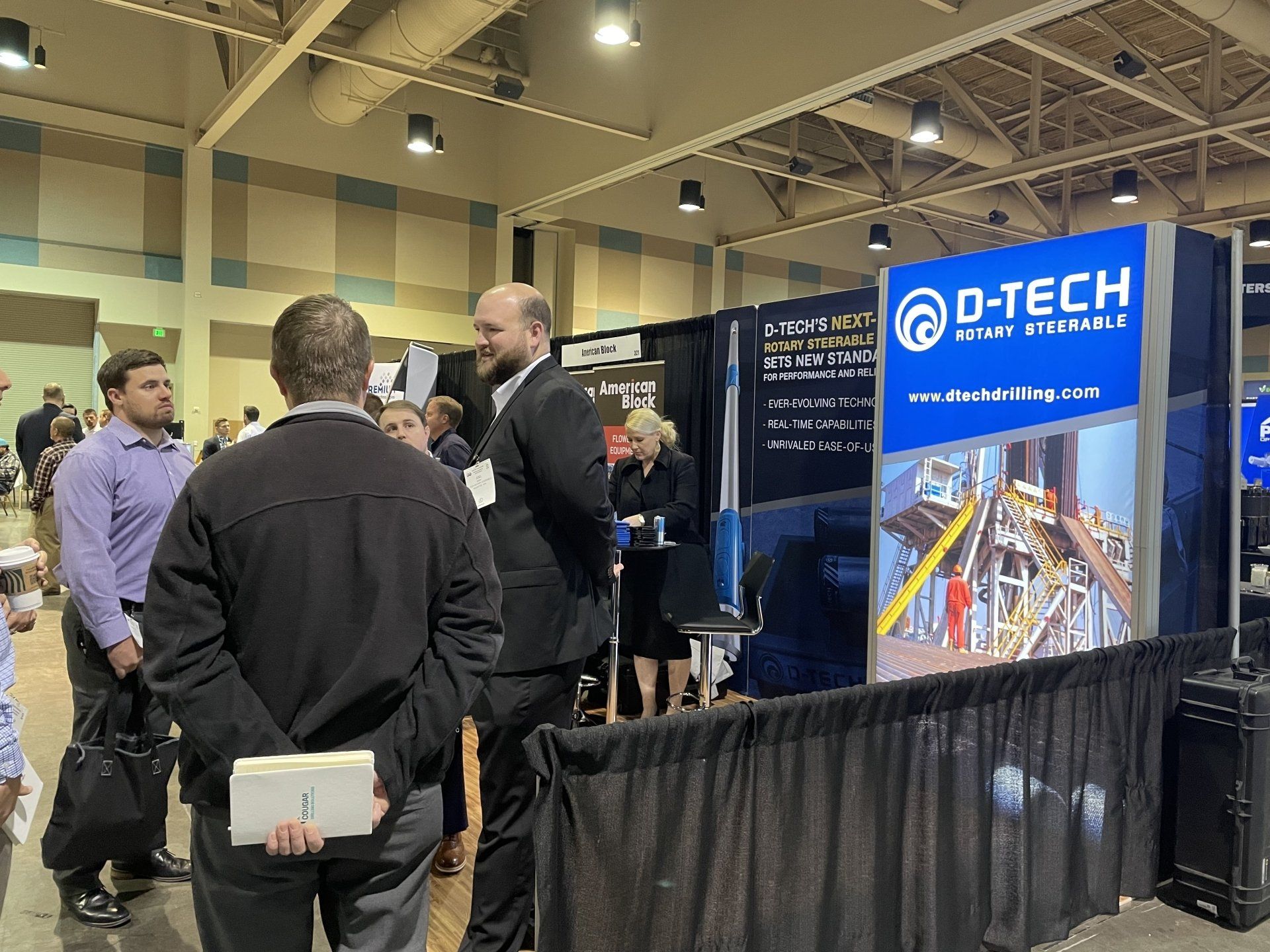 A group of people are standing around a booth at a convention.