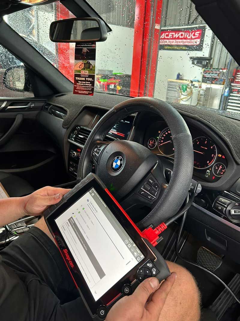 A Man in A Red Shirt Is Working On A Car Engine — Hervey Bay Service Centre in Pialba, QLD